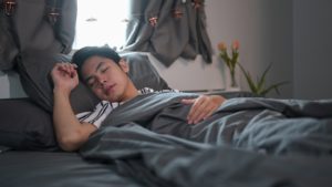 Young Asian man sleeping on comfortable bed.