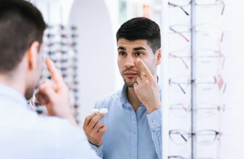 Man trying on contact eye lenses in optics shop